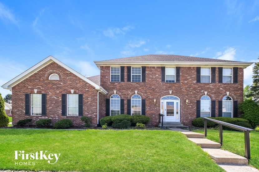 A brick house with a white door and windows is for sale.