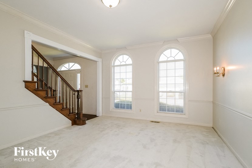 A spacious room with a staircase and two windows.