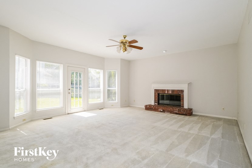 A spacious living room with a fireplace and a ceiling fan.