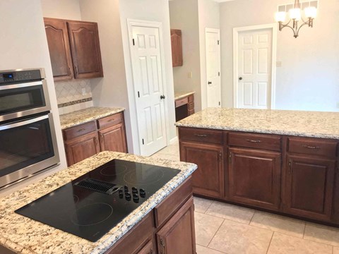 A kitchen with a black stove top and wooden cabinets.
