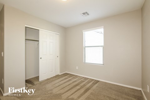 a bedroom with a closet and a window and a carpet