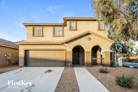 A beige house with a garage door and a driveway.