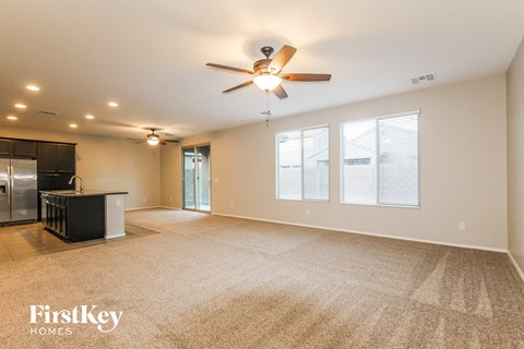 A spacious room with a ceiling fan and carpeted floor.