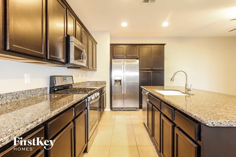 A kitchen with brown cabinets and granite countertops.