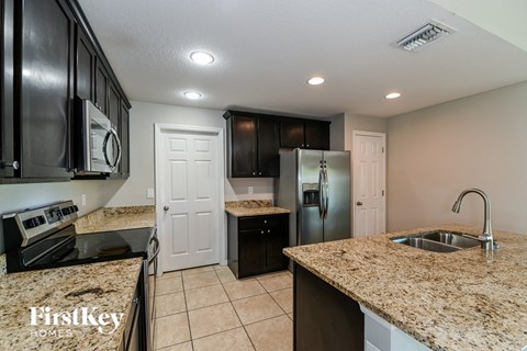 a kitchen with granite counter tops and a stainless steel refrigerator