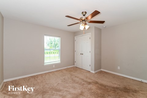 a bedroom with carpet and a ceiling fan and a closet