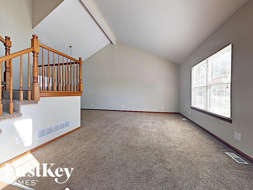 the upstairs living room has a large window and carpeted stairs