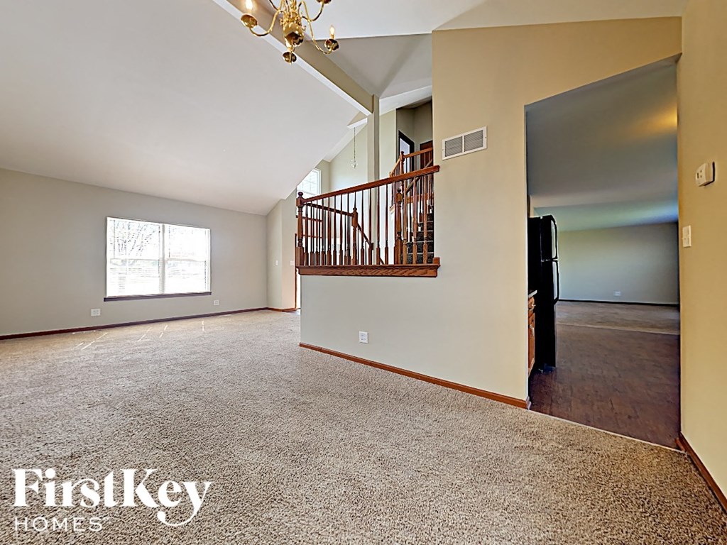 a large empty living room with a staircase in the corner