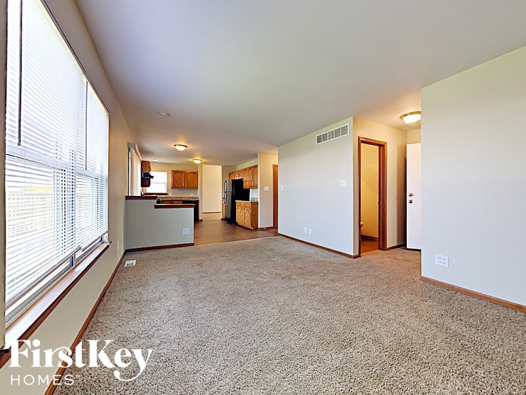 the living room and kitchen of an empty house with a large window