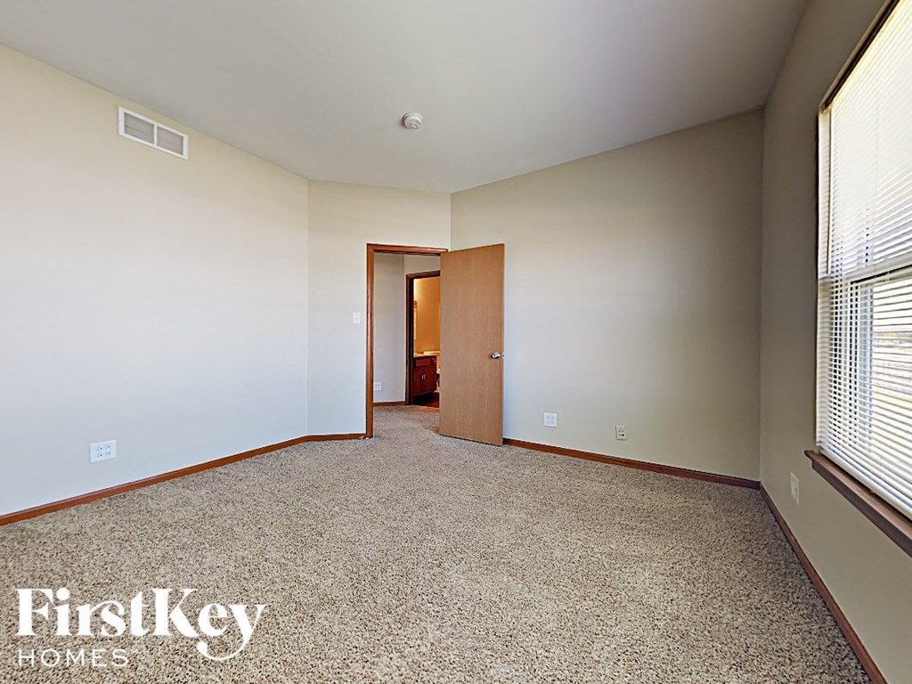 a bedroom with a carpeted floor and a door to a bathroom