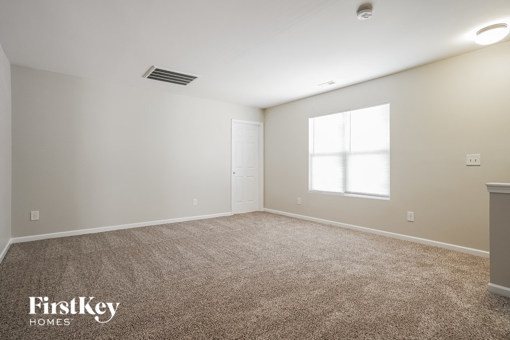 a spacious living room with carpet and a window