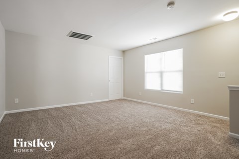 a spacious living room with carpet and a window