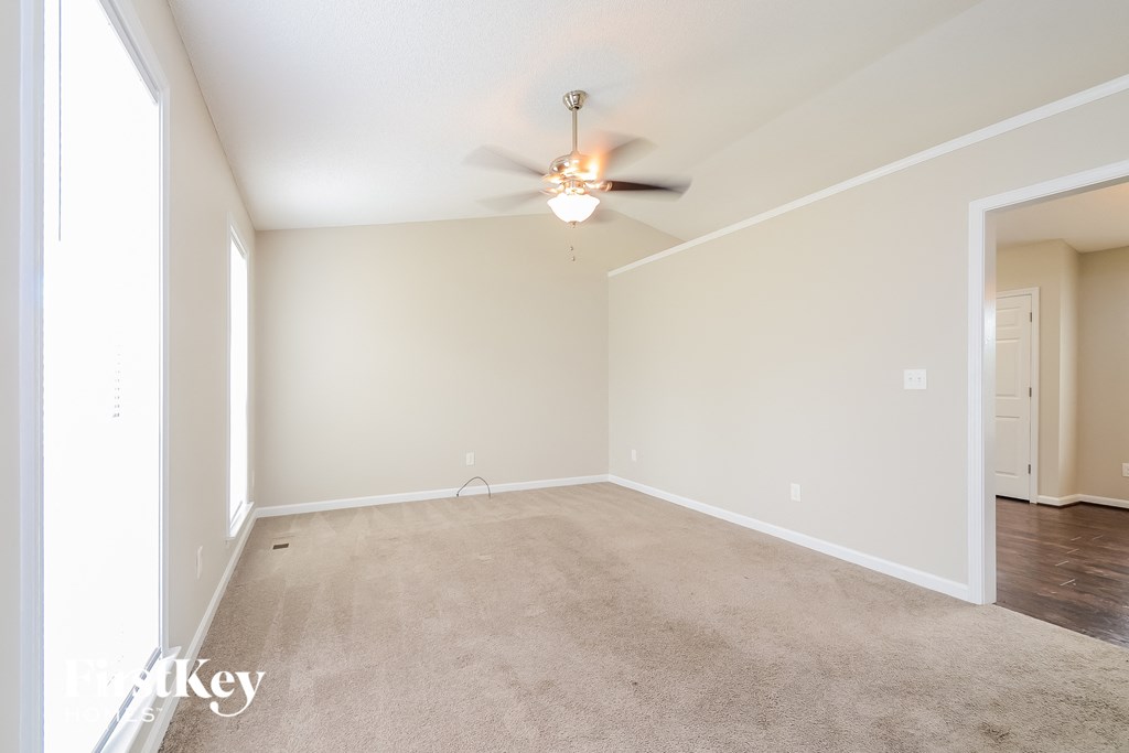a spacious living room with carpet and a ceiling fan