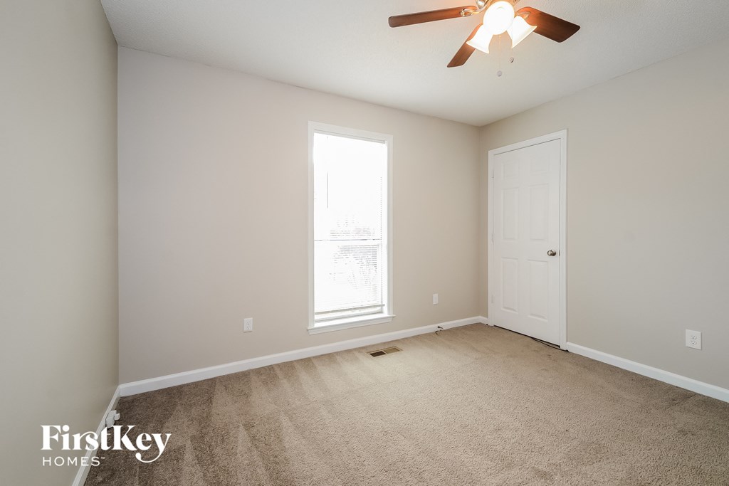 an empty room with a ceiling fan and a window