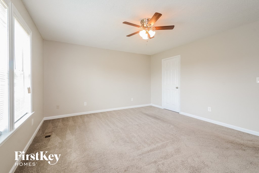 a spacious living room with carpet and a ceiling fan