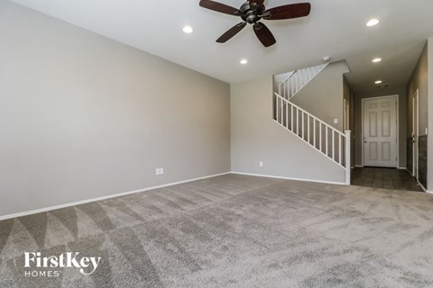 an empty living room with a ceiling fan and a staircase