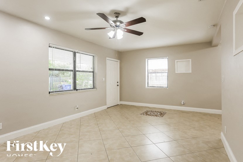 A spacious room with a ceiling fan and two windows.