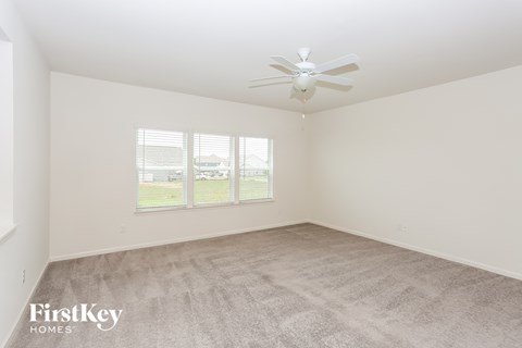 a spacious living room with carpet and a ceiling fan