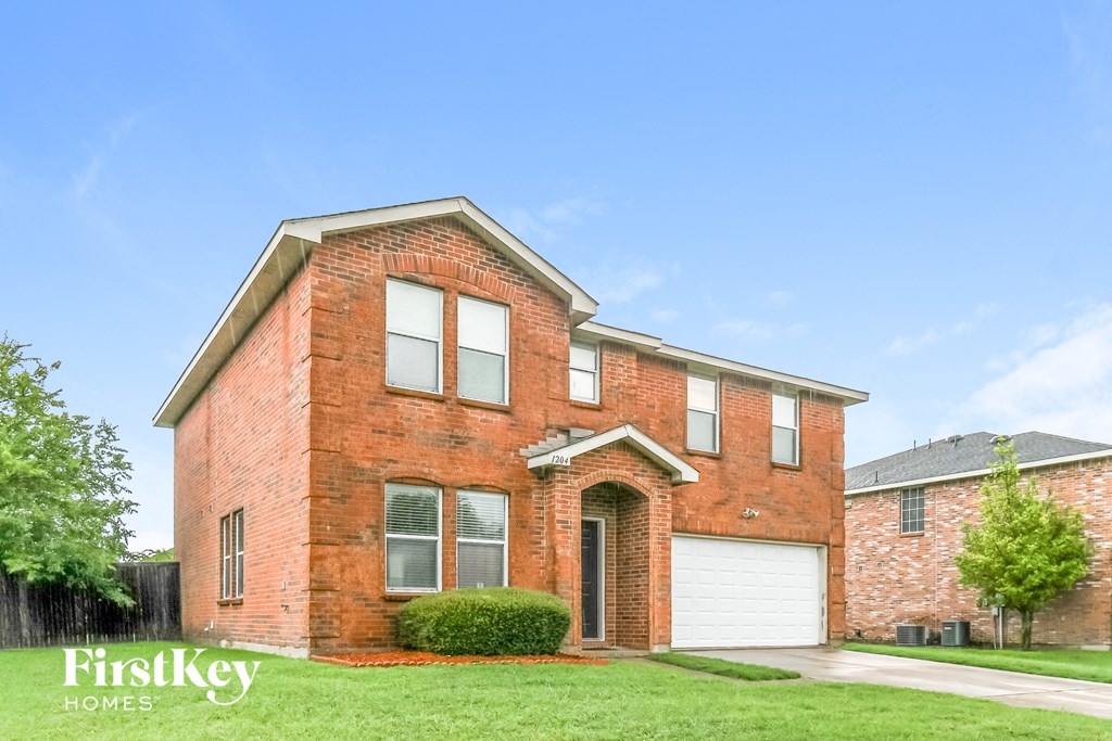 a brick house with a white garage door and a lawn