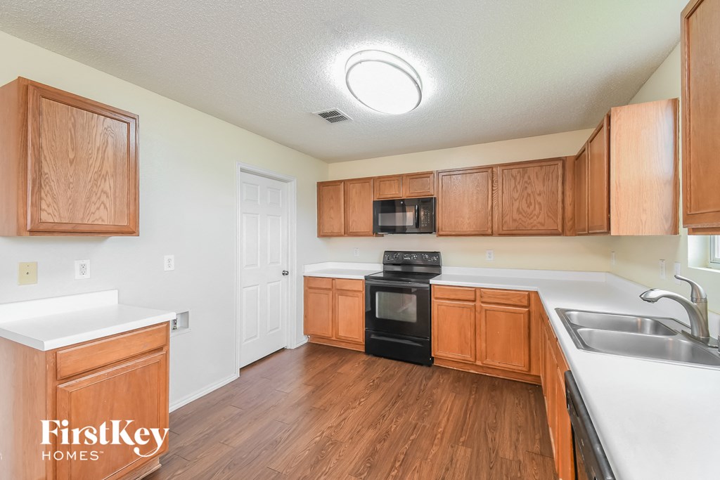 an empty kitchen with wood flooring and wooden cabinets