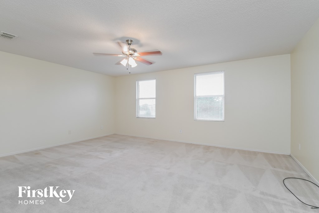 a spacious living room with white walls and a ceiling fan