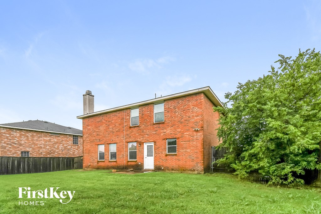 a red brick house with a green lawn and a blue sky