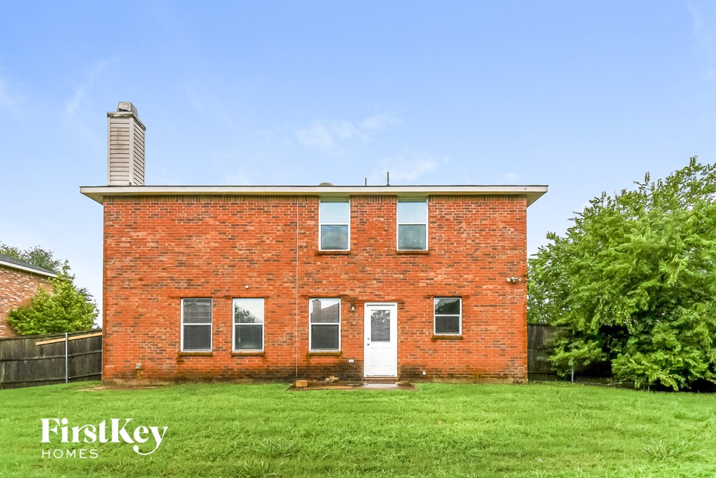 an old brick house with a white door and a green lawn