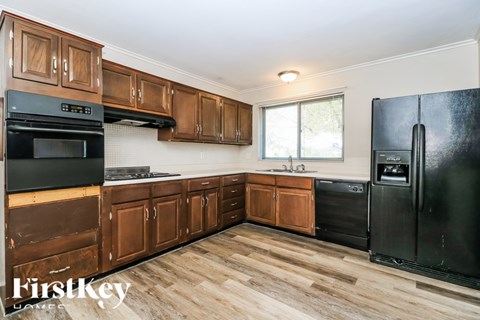 A kitchen with wooden cabinets and black appliances.