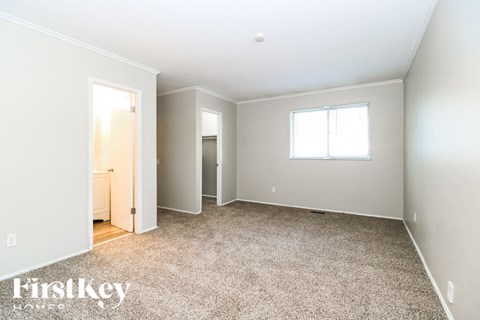 A spacious room with a carpeted floor and a window.