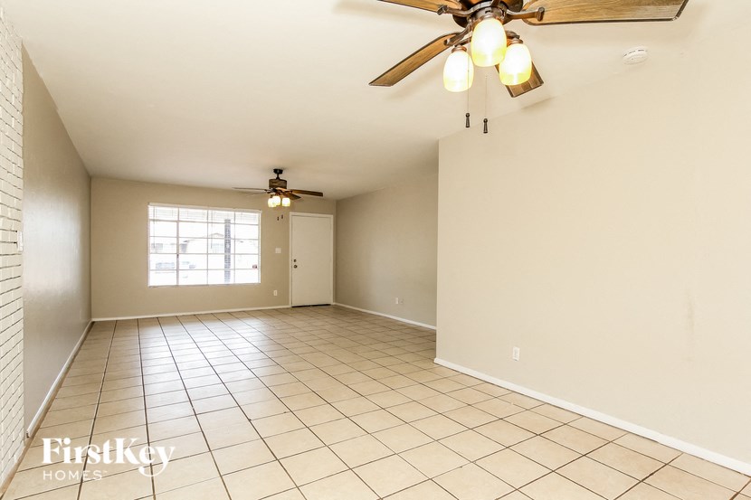 a empty living room with a ceiling fan and a tiled floor