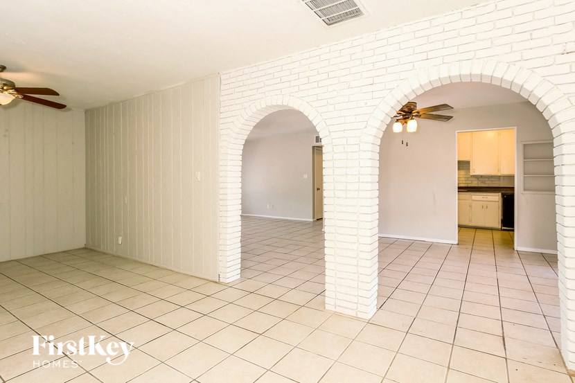 a kitchen and living room with white brick walls and tile floor