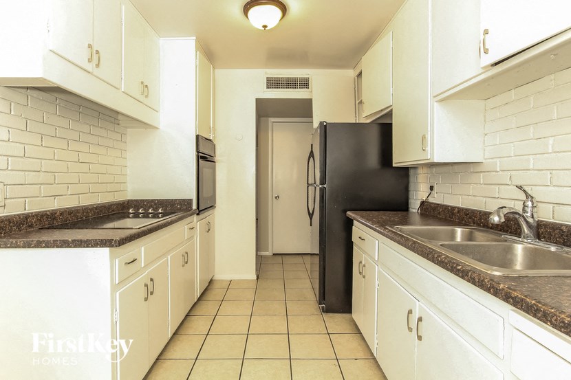 a kitchen with white cabinets and a black refrigerator