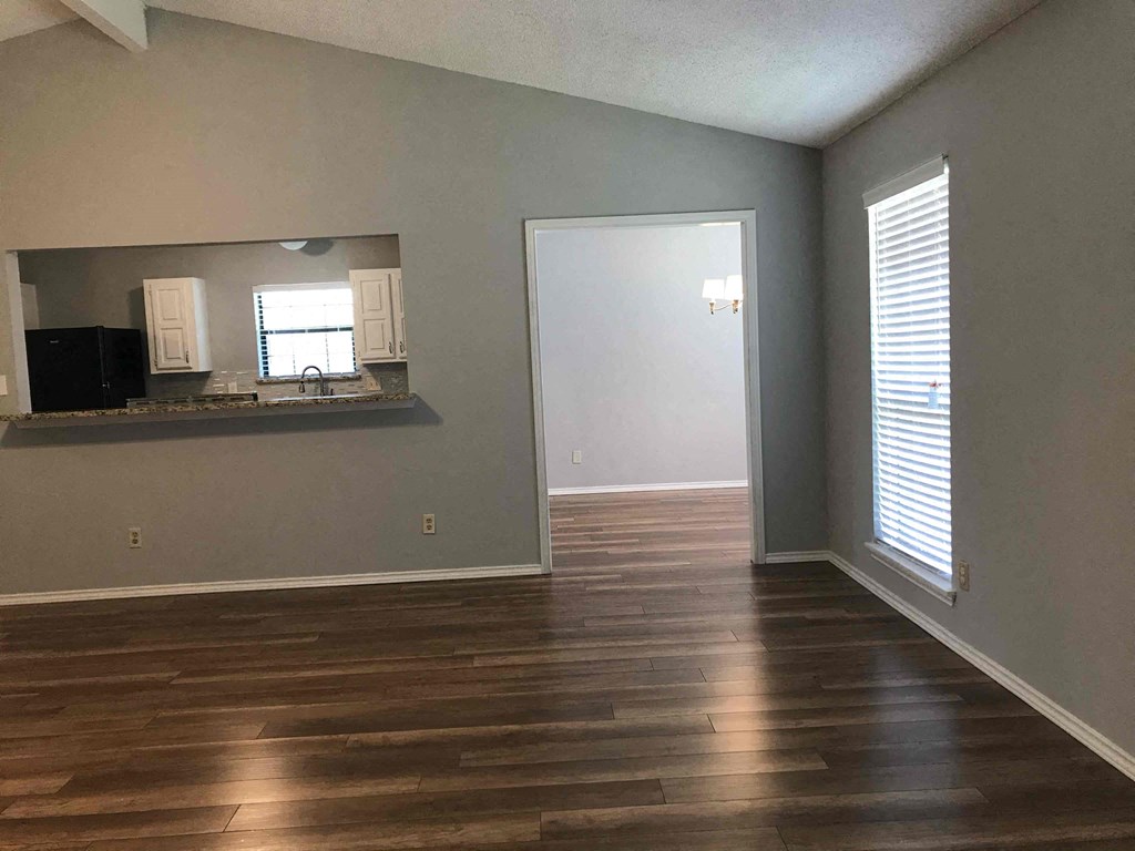 an empty living room with wood floors and a window