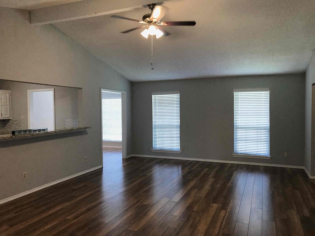 an empty living room with wood floors and a ceiling fan