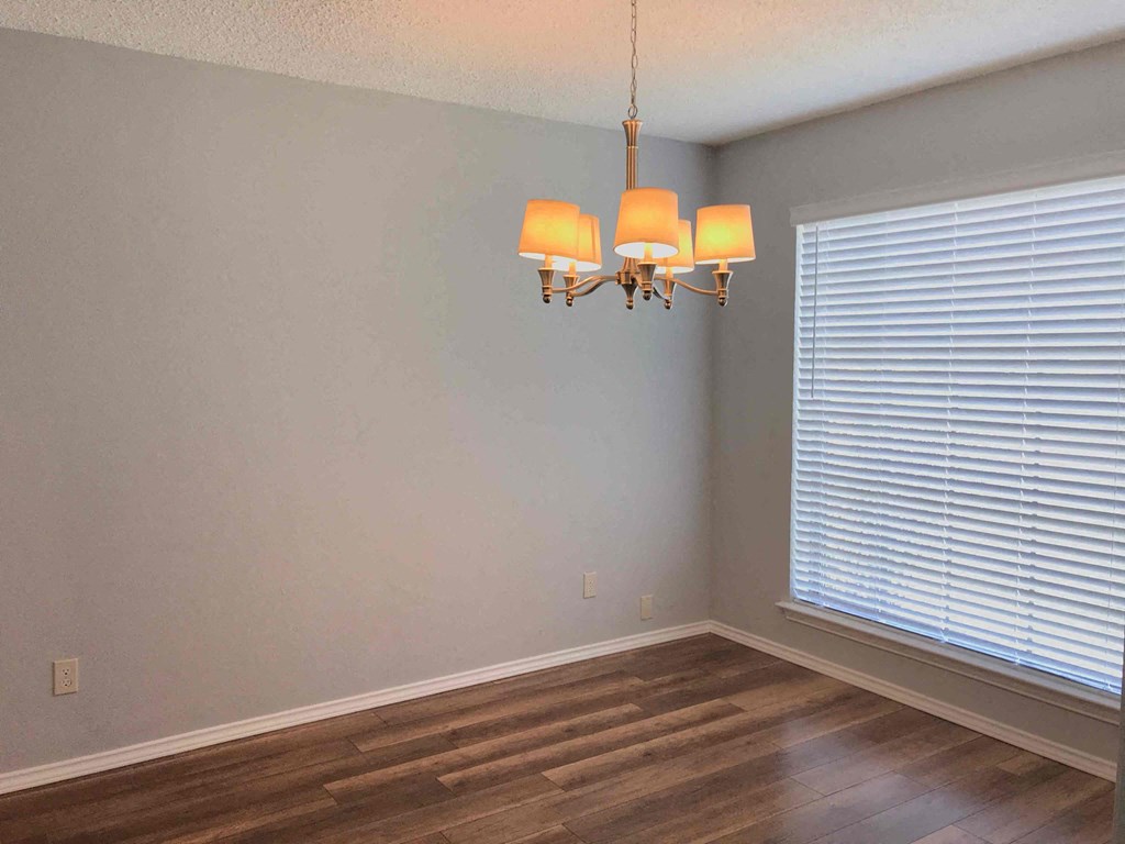 a living room with a large window and wooden floors and a chandelier
