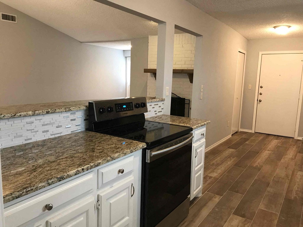 a kitchen with white cabinets and granite counter tops and a stove