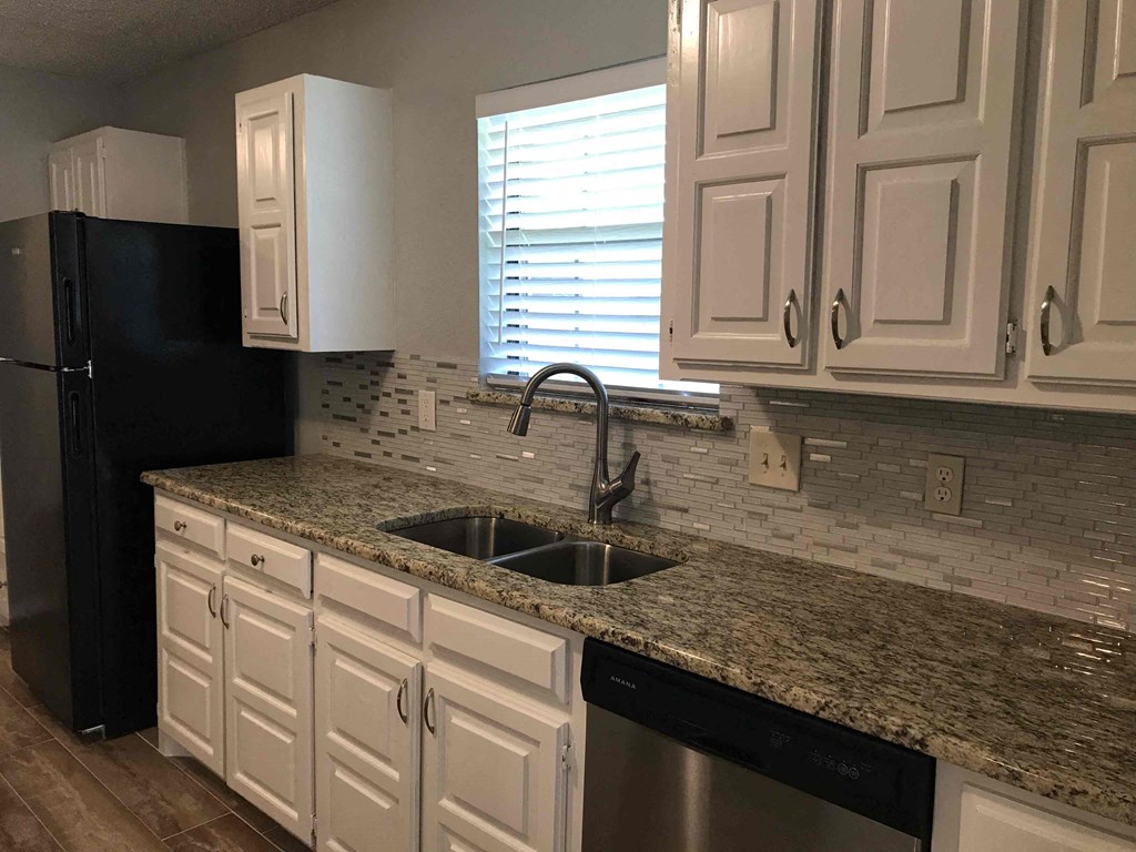 a kitchen with white cabinets and a granite counter top