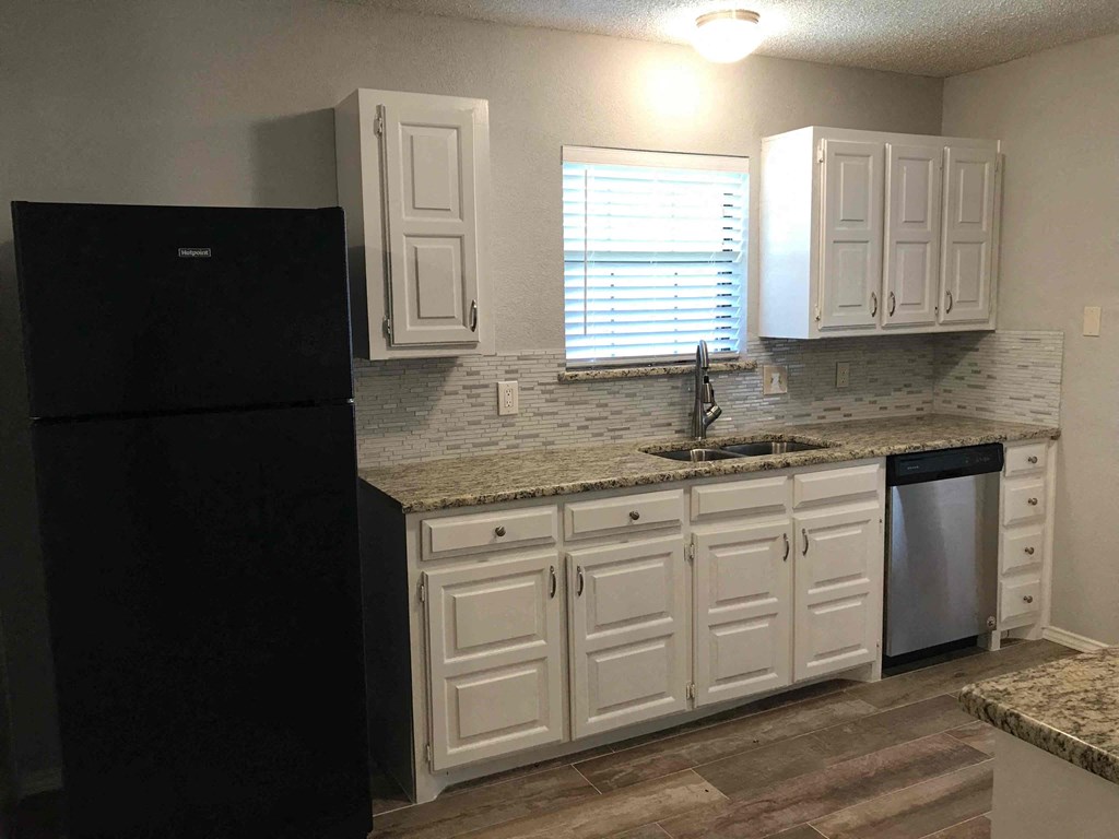 a kitchen with white cabinets and a black refrigerator