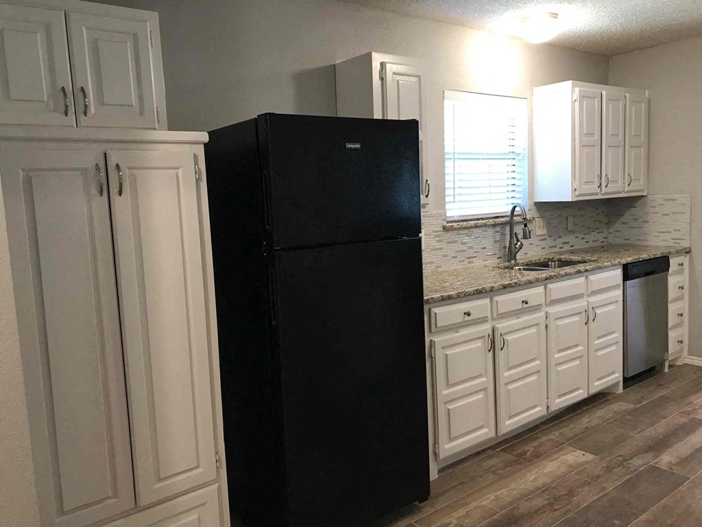 a kitchen with white cabinets and a black refrigerator