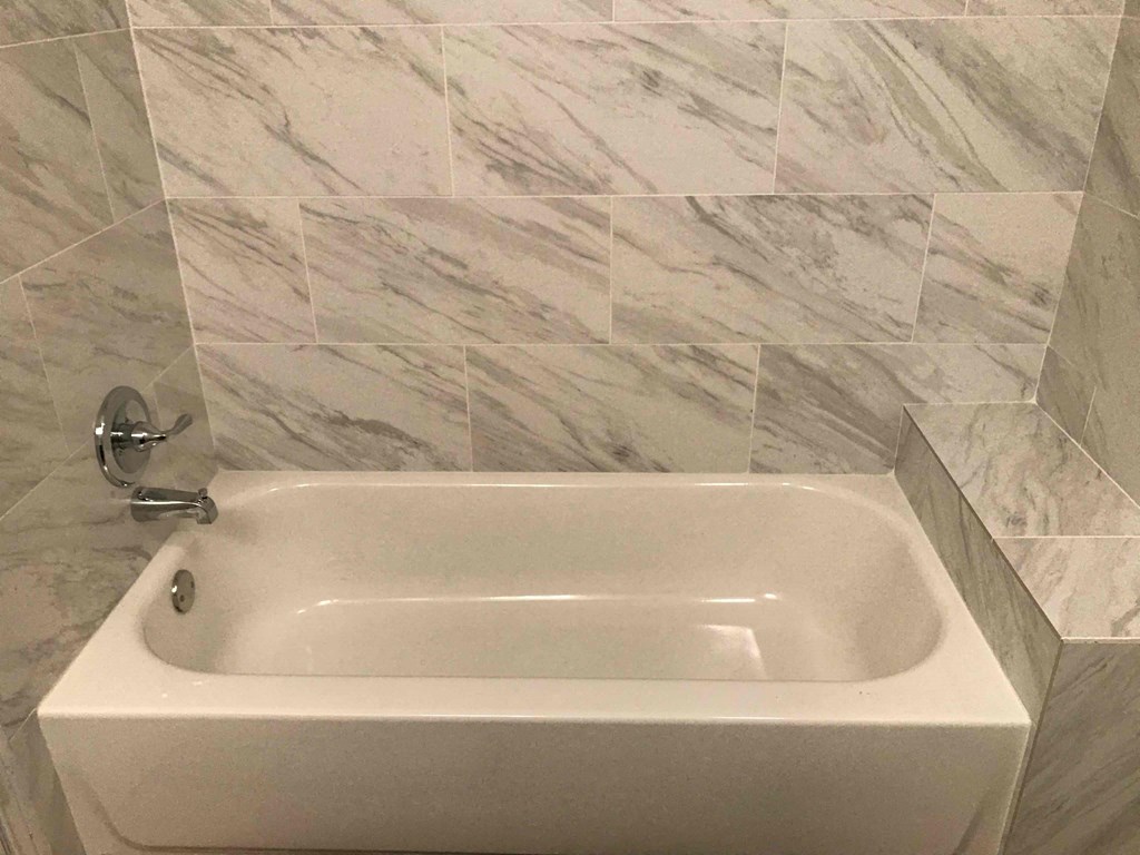 a white bath tub in a bathroom with marble walls