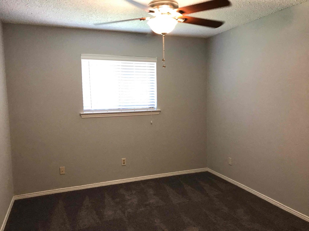 a empty room with a ceiling fan and a window