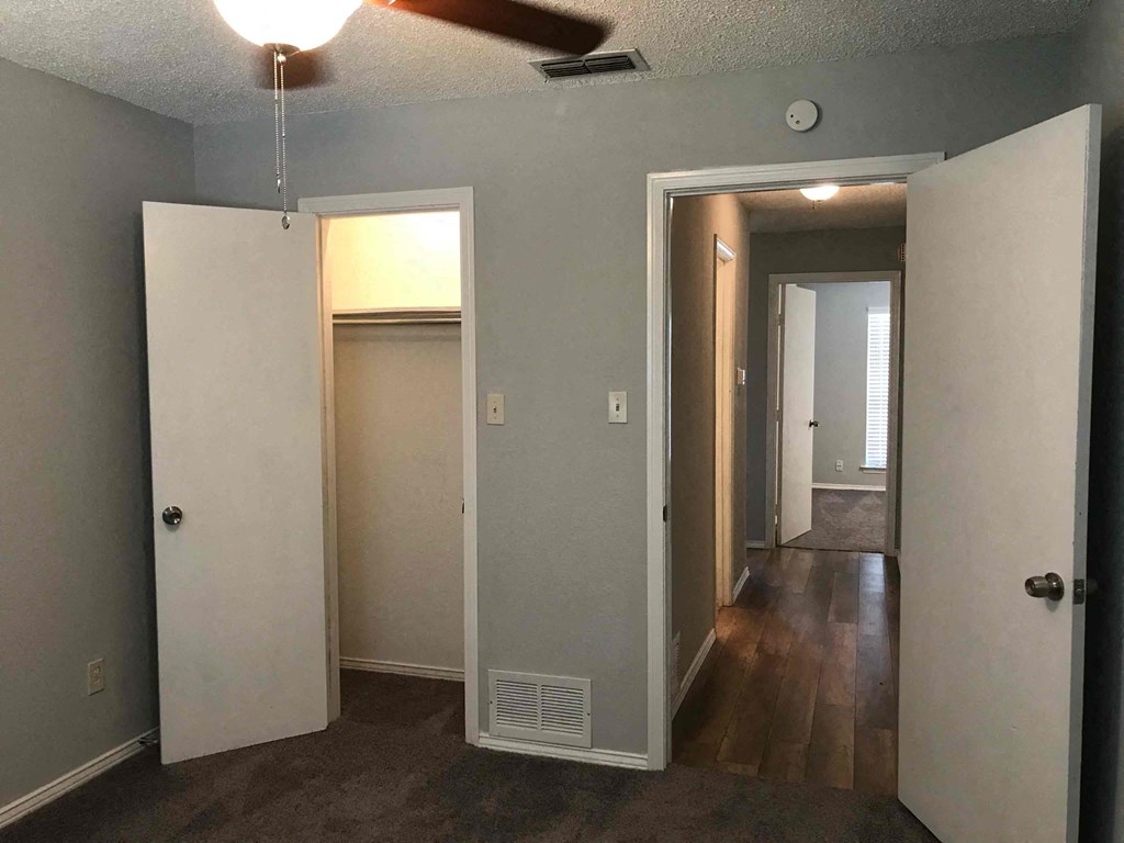 a room with a hallway with doors and a ceiling fan