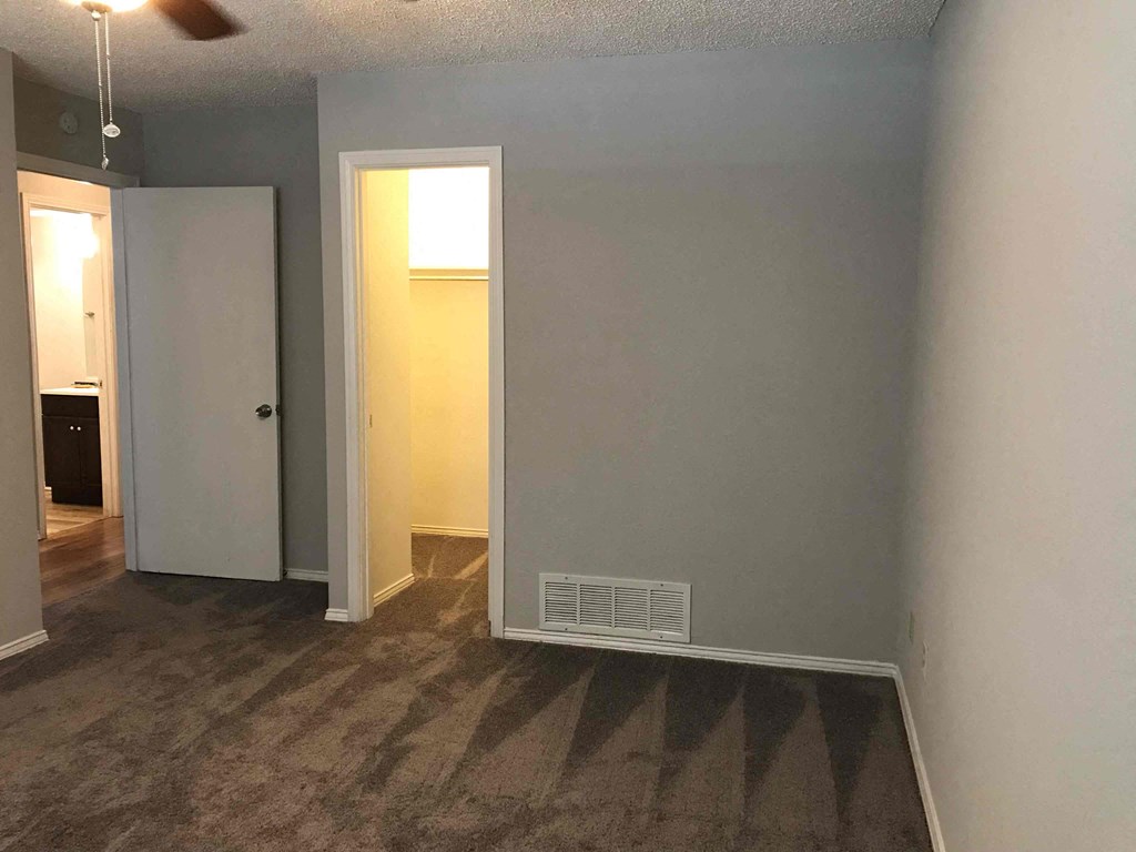 an empty room with a hallway and a door to a bathroom