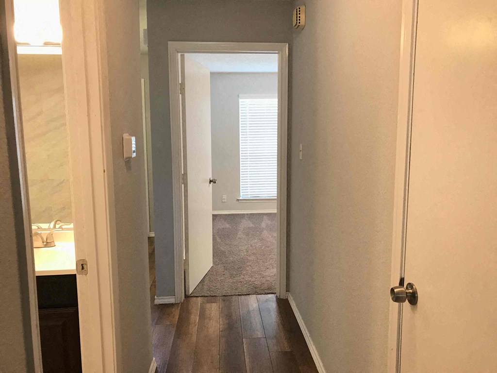 a small hallway with a door open to a bedroom and a door to a bathroom