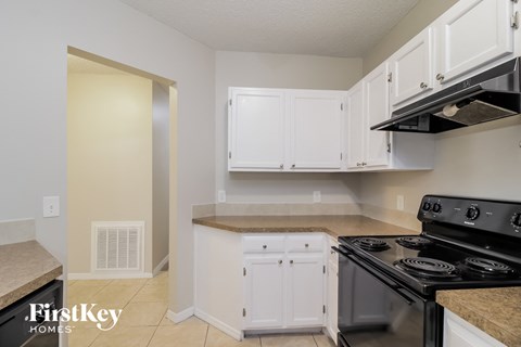 A kitchen with a black stove top oven and white cabinets.