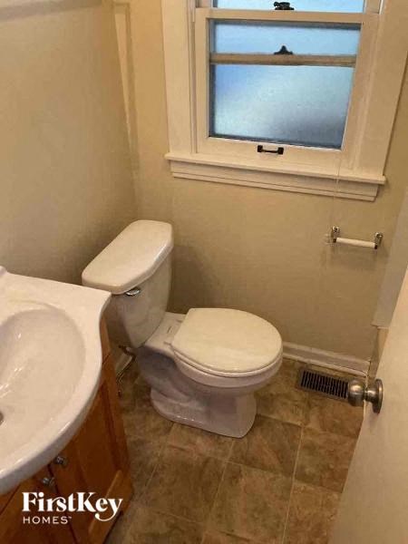 A small bathroom with a toilet, sink, and a window.