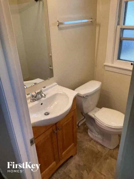 A bathroom with a toilet, sink, and mirror.