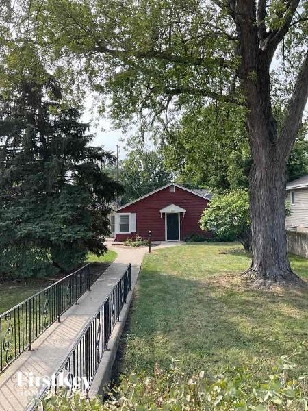 A red house with a white door is surrounded by trees.