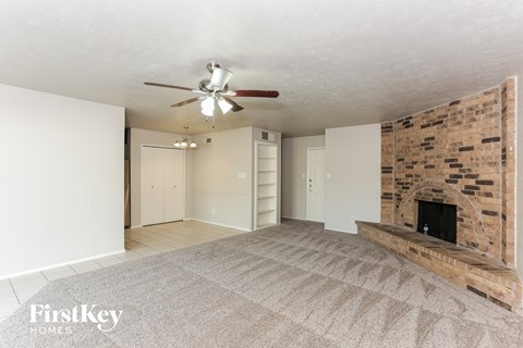 a living room with a brick fireplace and a ceiling fan