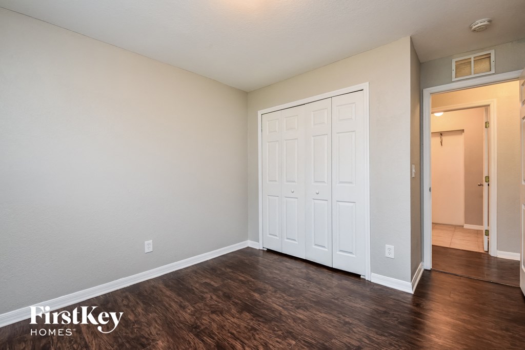 the living room of an apartment with a white door and wood flooring